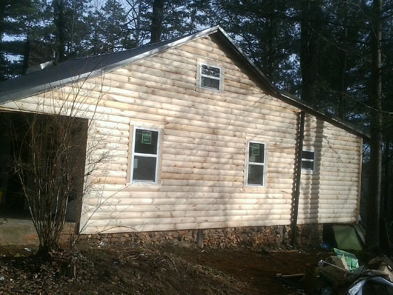 New log siding and dark metal roofing on a gable end in Deep Gap