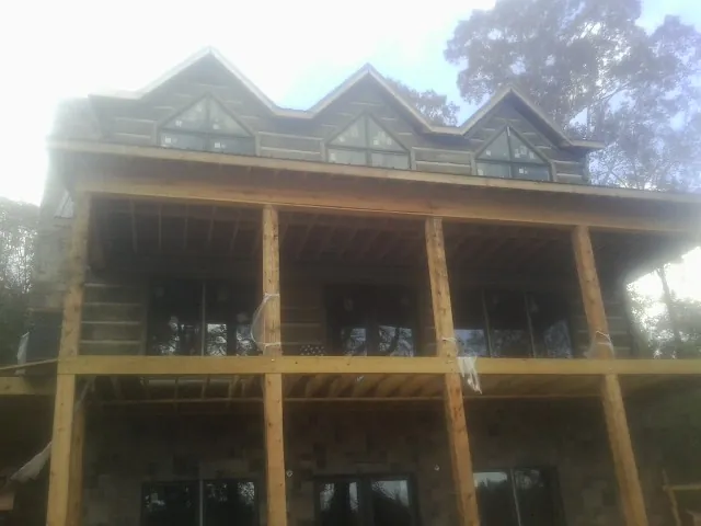 Dormers and porch framing on a large log home under construction — Roof Coating work by our crew in Deep Gap