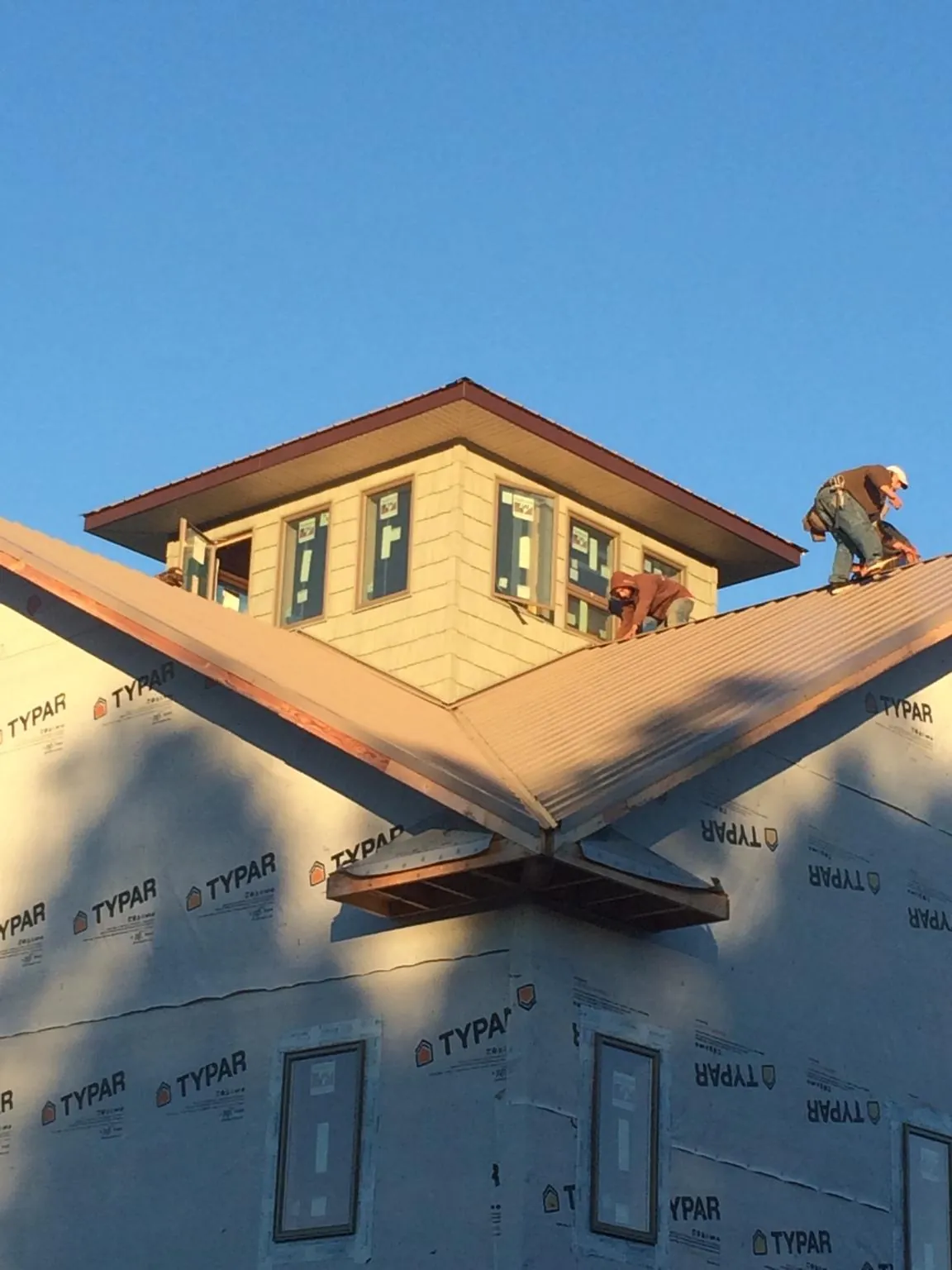 Roofers working around a rooftop cupola on a new metal roof at sunset — Roof Waterproofing in Deep Gap by Roofing Brothers